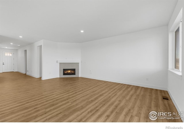unfurnished living room with recessed lighting, light wood finished floors, baseboards, and a fireplace