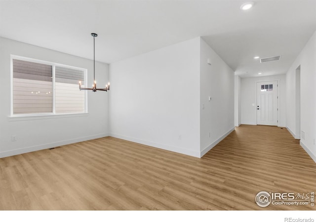empty room featuring a chandelier, light wood-type flooring, recessed lighting, and baseboards