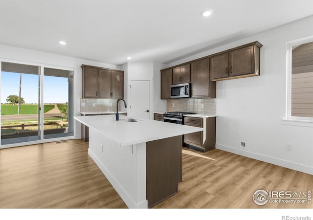 kitchen with stainless steel appliances, a sink, dark brown cabinetry, backsplash, and recessed lighting