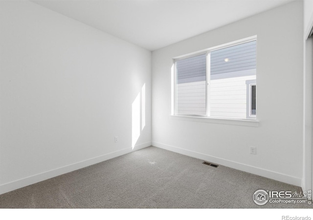 empty room featuring carpet and baseboards