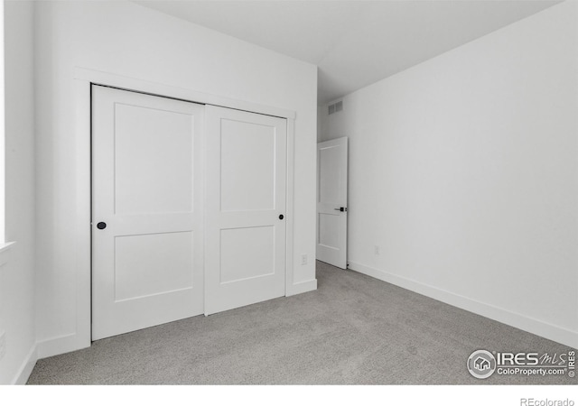 unfurnished bedroom featuring carpet, a closet, and baseboards