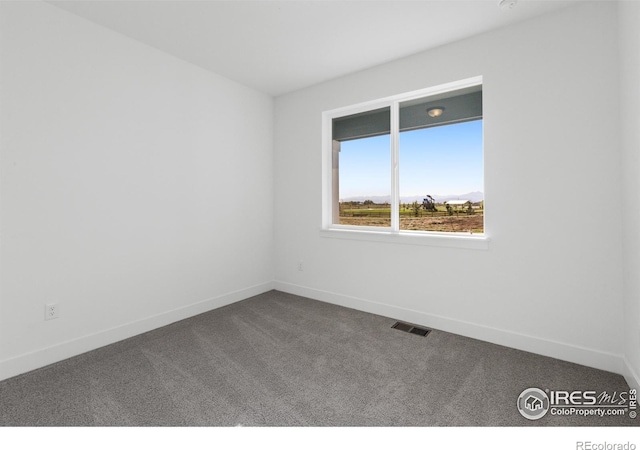 empty room featuring dark colored carpet and baseboards