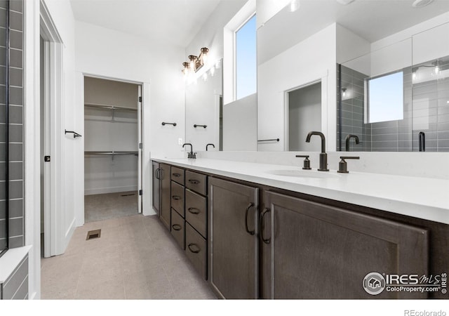 bathroom featuring double vanity, a spacious closet, and an enclosed shower