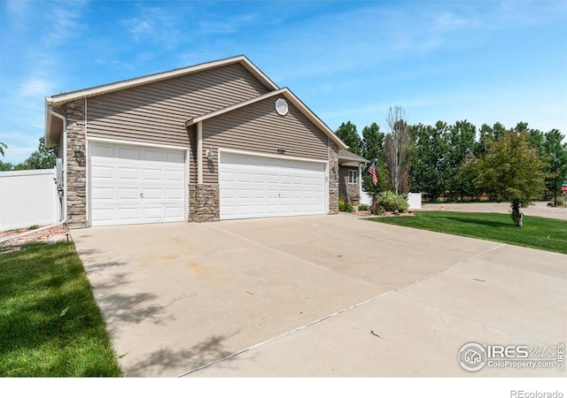 7037 Raleigh St, Wellington, CO 80549 - view of property exterior with an attached garage, driveway, and stone siding