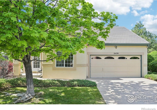 view of front of property with stucco siding, an attached garage, concrete driveway, and a tiled roof