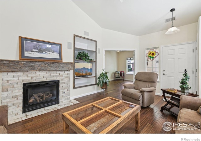 living room with wood finished floors, a stone fireplace, and baseboards