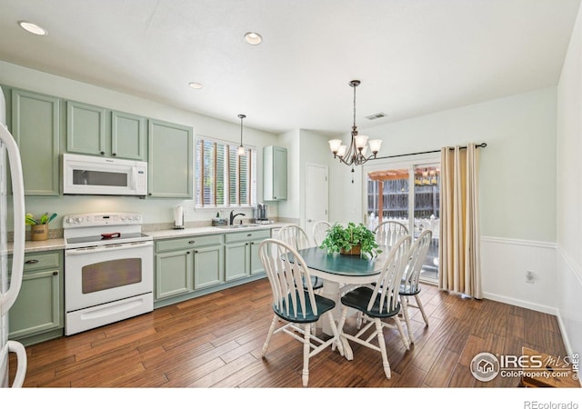 kitchen featuring white appliances, green cabinets, a sink, a chandelier, and a wainscoted wall