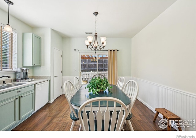 dining area with a chandelier, wainscoting, dark wood finished floors, and healthy amount of natural light