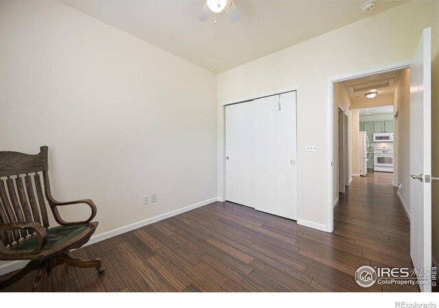 living area with dark wood-type flooring, a ceiling fan, and baseboards
