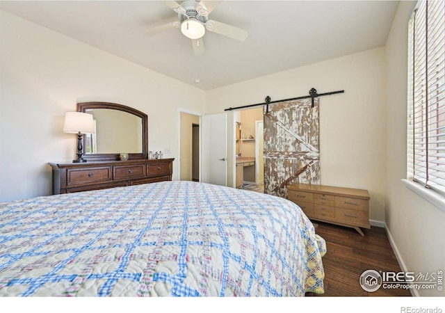 bedroom with wood finished floors, baseboards, a barn door, a ceiling fan, and connected bathroom