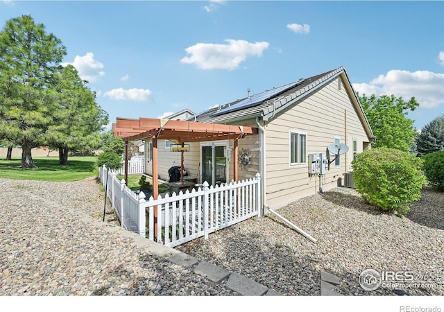 back of property featuring roof mounted solar panels, a pergola, a patio area, and central AC