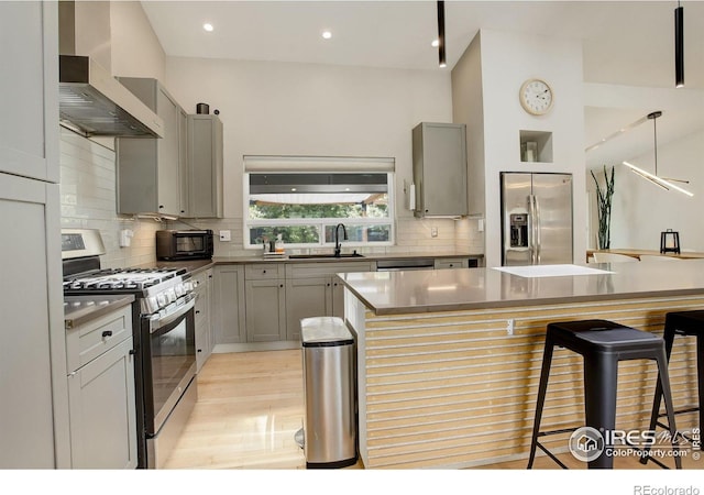 6862 Roaring Fork Trl, Boulder, CO 80301 - kitchen featuring appliances with stainless steel finishes, wall chimney exhaust hood, a sink, a kitchen breakfast bar, and decorative backsplash