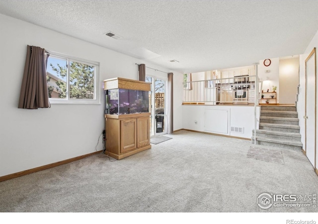 710 Sedge Way, Lafayette, CO 80026 - unfurnished living room featuring carpet, healthy amount of natural light, a textured ceiling, and stairs
