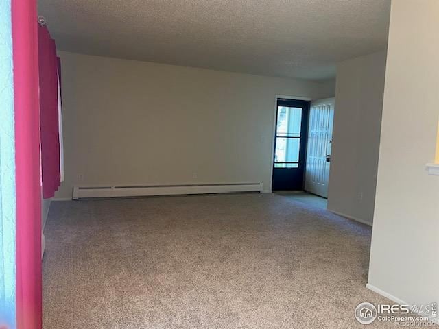 carpeted spare room featuring a textured ceiling, baseboard heating, and baseboards