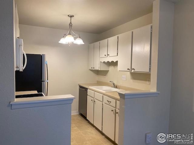kitchen featuring a sink, appliances with stainless steel finishes, light countertops, white cabinetry, and decorative light fixtures