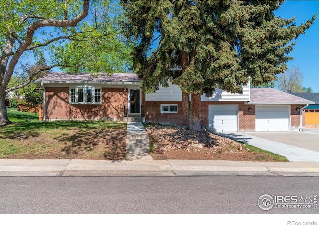 split level home with concrete driveway and brick siding