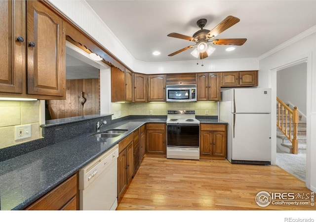 kitchen with white appliances, a sink, tasteful backsplash, brown cabinets, and a ceiling fan