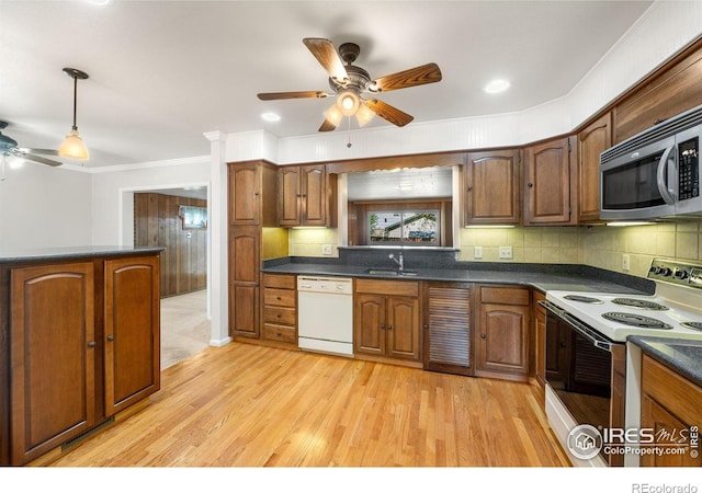 kitchen featuring white appliances, a ceiling fan, a sink, dark countertops, and ornamental molding