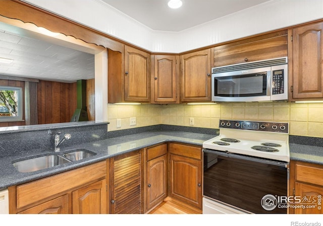 kitchen with stainless steel microwave, white electric range, a sink, decorative backsplash, and brown cabinets