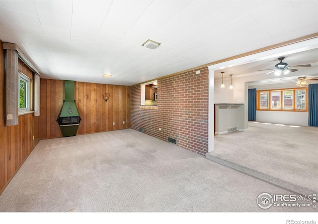 unfurnished living room with carpet floors, a ceiling fan, and wood walls