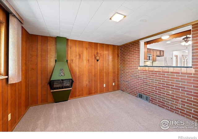 carpeted spare room featuring wooden walls and brick wall