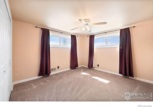 empty room with a ceiling fan, carpet floors, healthy amount of natural light, and baseboards