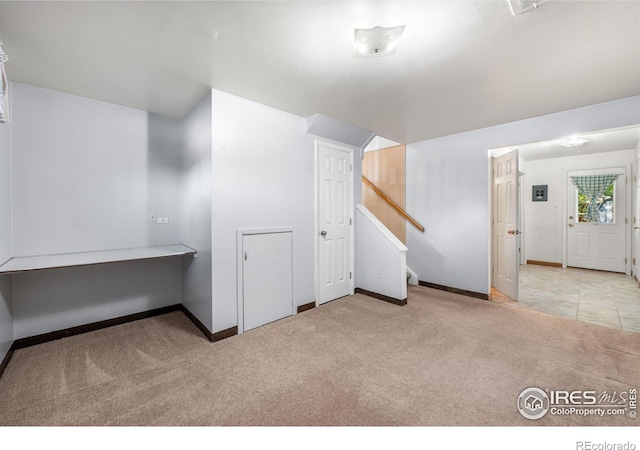 basement featuring carpet, baseboards, and stairway