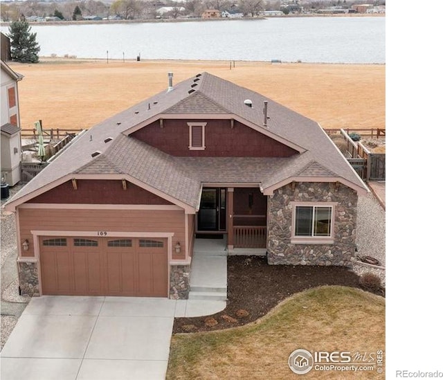 109 Veronica Dr, Windsor, CO 80550 - view of front of home featuring stone siding, driveway, a water view, and roof with shingles