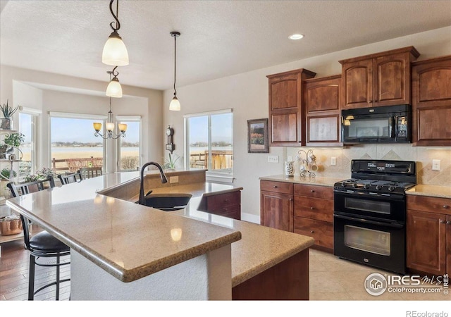 109 Veronica Dr, Windsor, CO 80550 - kitchen with black appliances, a sink, an island with sink, recessed lighting, and a chandelier