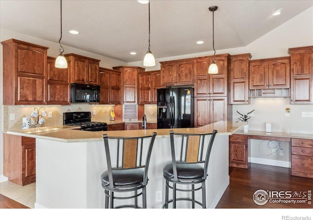 109 Veronica Dr, Windsor, CO 80550 - kitchen featuring black appliances, a kitchen island with sink, recessed lighting, tasteful backsplash, and dark wood-type flooring