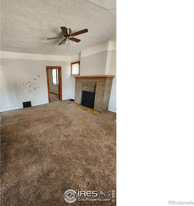 unfurnished living room featuring a ceiling fan, a brick fireplace, a textured ceiling, and carpet