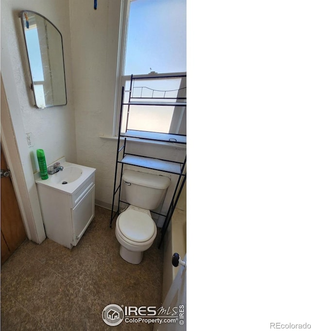 bathroom with toilet, vanity, and baseboards