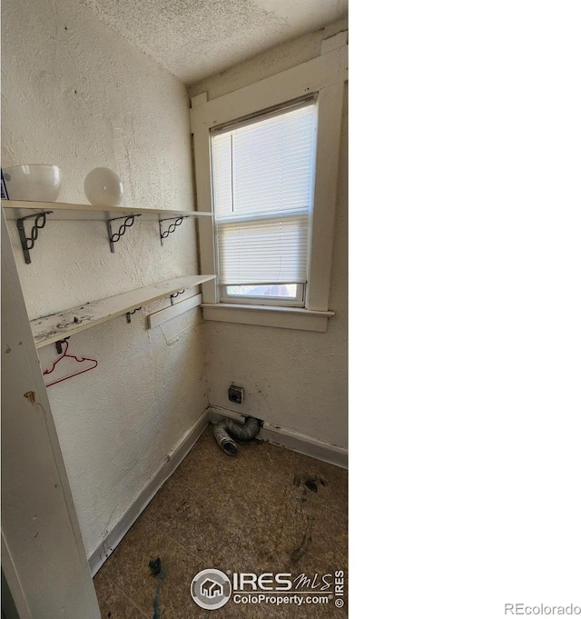 washroom with a textured wall, baseboards, and a textured ceiling