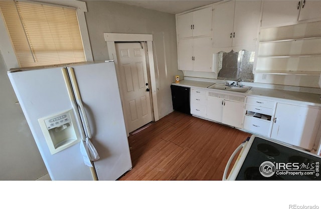 kitchen featuring white fridge with ice dispenser, a sink, light wood-style floors, and white cabinetry