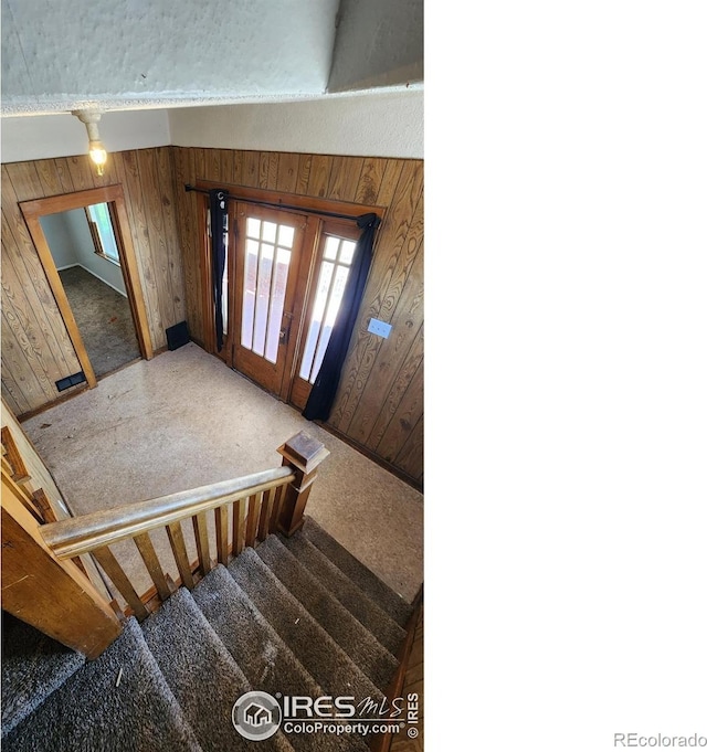 foyer with carpet, wood walls, and french doors