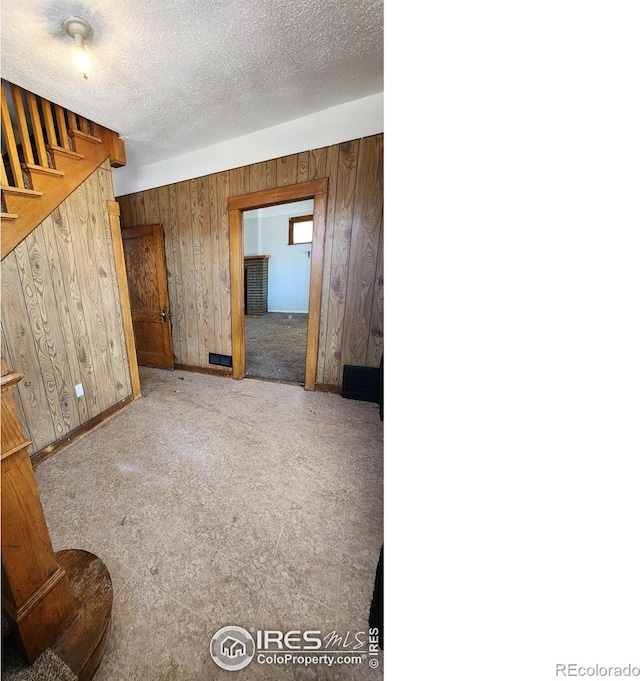 unfurnished living room with wood walls, baseboards, and a textured ceiling