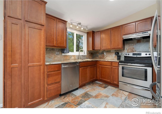 kitchen featuring stainless steel appliances, a sink, under cabinet range hood, and decorative backsplash