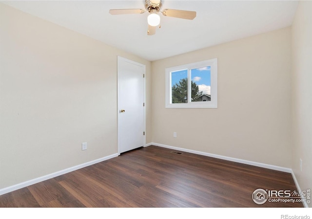 spare room with baseboards, dark wood finished floors, and a ceiling fan