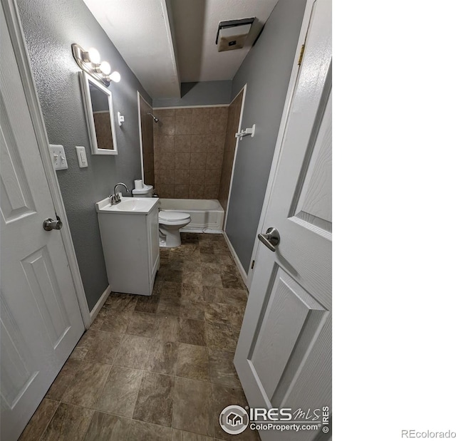full bath featuring toilet, baseboards, vanity, stone finish flooring, and  shower combination