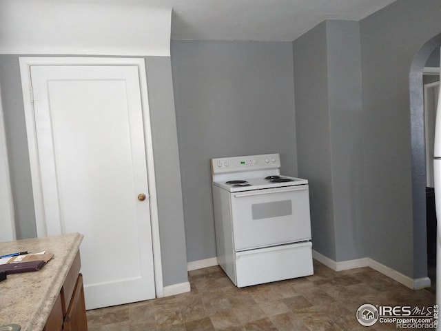 kitchen with electric stove, arched walkways, baseboards, and light countertops