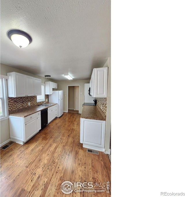 214 Charmony Pl, Sterling, CO 80751 - kitchen featuring freestanding refrigerator, a sink, black dishwasher, white cabinets, and a textured ceiling