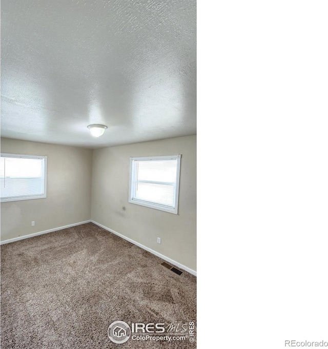 214 Charmony Pl, Sterling, CO 80751 - carpeted empty room with baseboards, healthy amount of natural light, and a textured ceiling