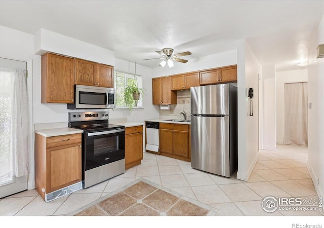 200 Perry St, Denver, CO 80219 - kitchen with stainless steel appliances, a sink, light countertops, and brown cabinetry