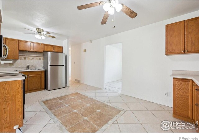 200 Perry St, Denver, CO 80219 - kitchen with stainless steel appliances, ceiling fan, brown cabinetry, a sink, and light countertops
