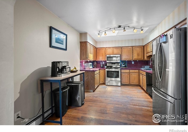 2702 W 23rd St, Greeley, CO 80634 - kitchen featuring stainless steel appliances, baseboard heating, light wood-style floors, brown cabinets, and backsplash