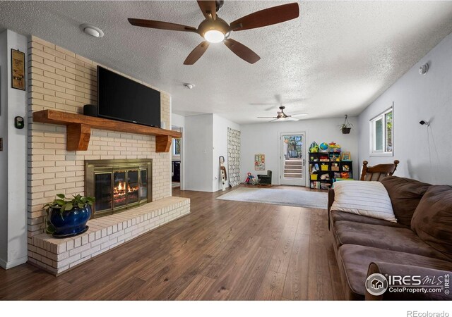 2702 W 23rd St, Greeley, CO 80634 - living area featuring a fireplace, ceiling fan, a textured ceiling, and wood finished floors
