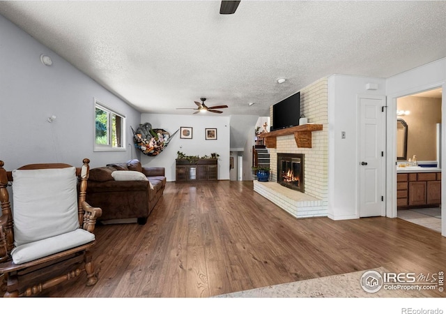 2702 W 23rd St, Greeley, CO 80634 - living room with ceiling fan, wood finished floors, a textured ceiling, and a brick fireplace