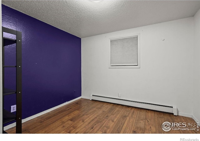 2702 W 23rd St, Greeley, CO 80634 - unfurnished room with a baseboard heating unit, wood finished floors, baseboards, and a textured ceiling