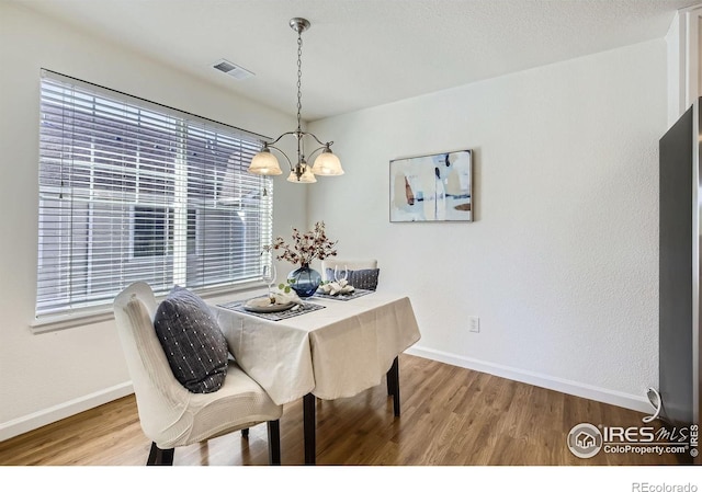 dining space with a chandelier, wood finished floors, baseboards, and healthy amount of natural light