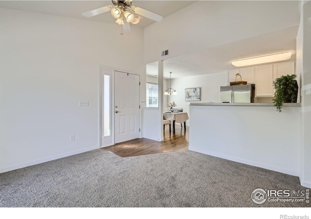 entrance foyer featuring dark carpet, ceiling fan, and baseboards